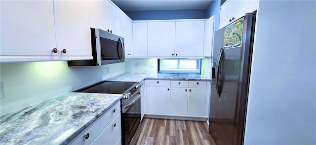 kitchen featuring light stone countertops, appliances with stainless steel finishes, white cabinets, and light hardwood / wood-style floors