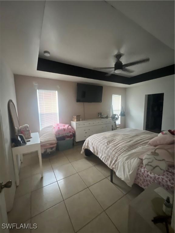 tiled bedroom featuring a raised ceiling and ceiling fan