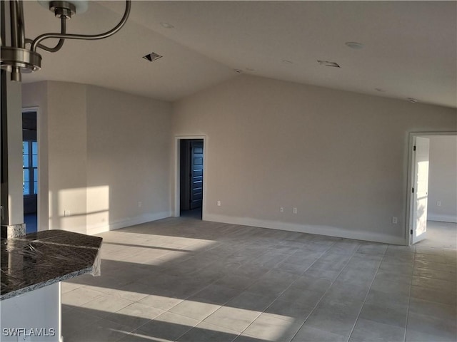 empty room featuring lofted ceiling, visible vents, and baseboards