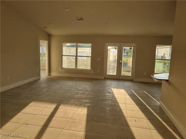 tiled empty room featuring french doors and baseboards