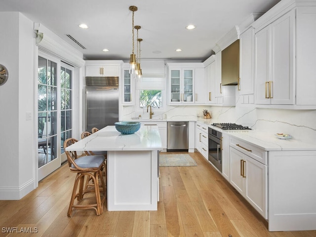 kitchen featuring a kitchen island, white cabinetry, appliances with stainless steel finishes, and light hardwood / wood-style floors