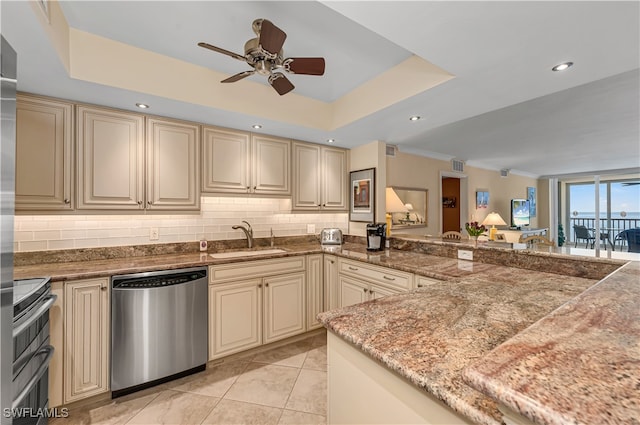 kitchen featuring dishwasher, cream cabinets, sink, a tray ceiling, and range