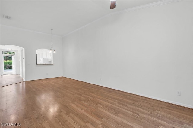 spare room with wood-type flooring, ceiling fan with notable chandelier, vaulted ceiling, and crown molding