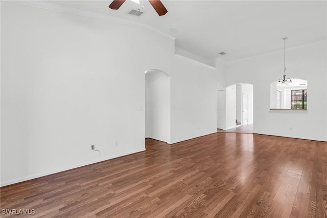 unfurnished living room with ceiling fan with notable chandelier, wood-type flooring, and ornamental molding