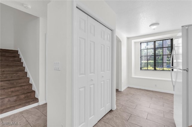 hall with light tile patterned floors and a textured ceiling