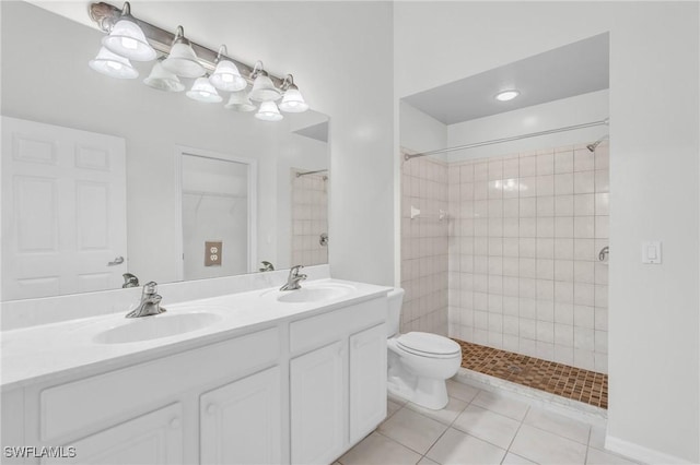 bathroom featuring a tile shower, tile patterned floors, vanity, and toilet