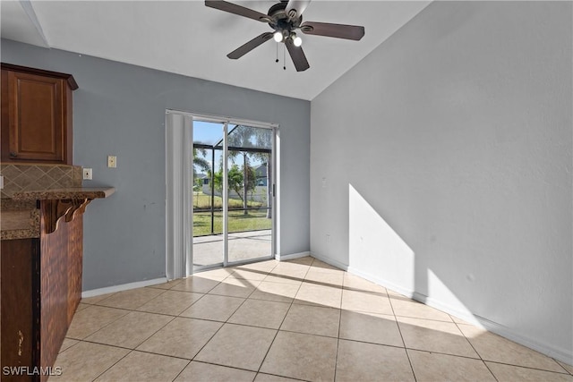 unfurnished dining area featuring ceiling fan, light tile patterned floors, and vaulted ceiling