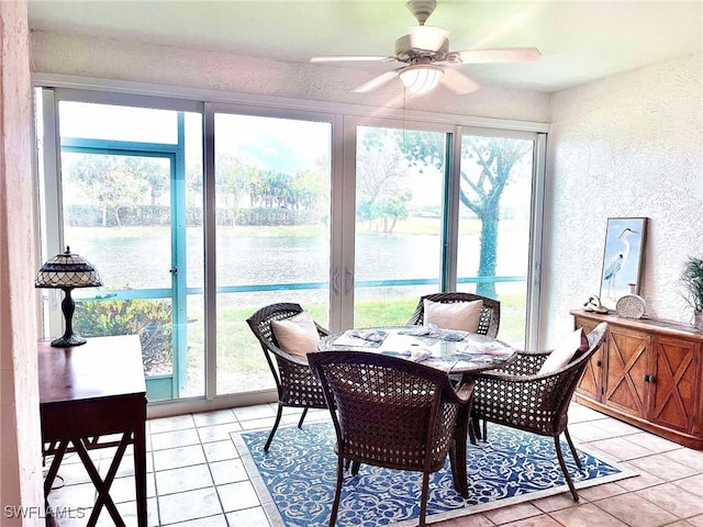 sunroom / solarium featuring ceiling fan and a water view