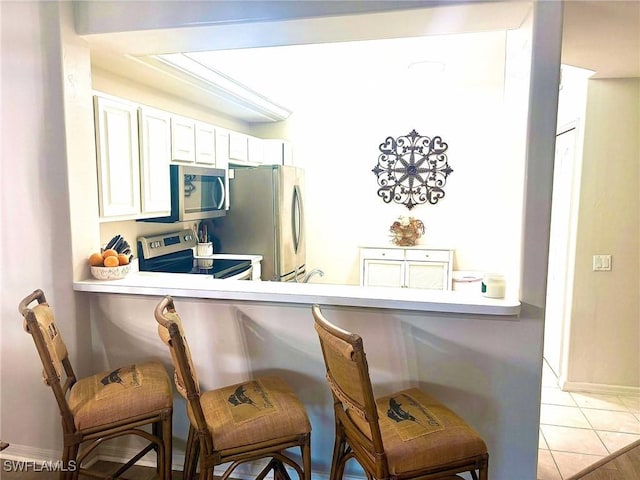 kitchen with white cabinetry, stainless steel appliances, kitchen peninsula, and a breakfast bar area