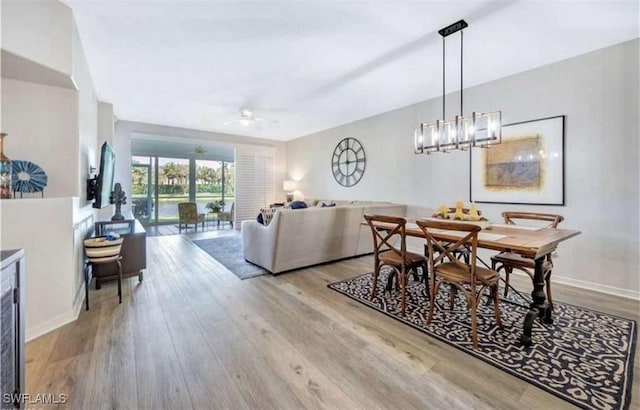 dining room featuring ceiling fan with notable chandelier and light hardwood / wood-style floors