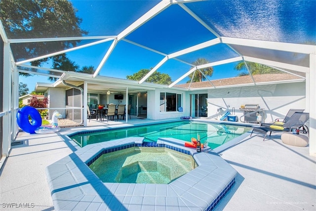 view of pool with a patio area, an in ground hot tub, ceiling fan, and glass enclosure