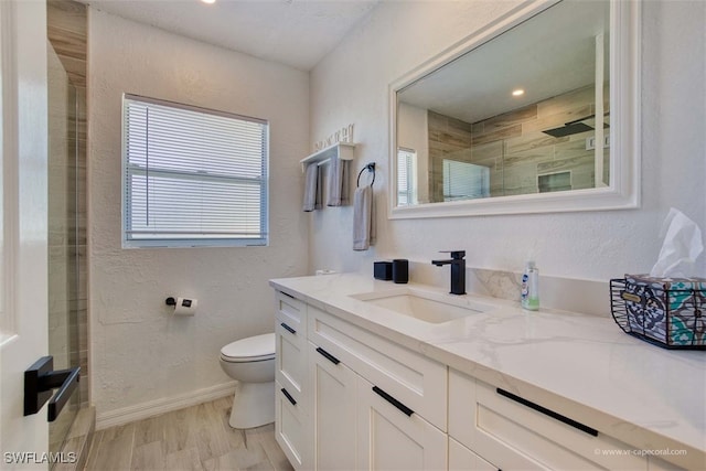 bathroom with walk in shower, vanity, wood-type flooring, and toilet