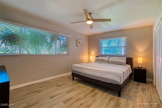 bedroom featuring multiple windows, a closet, hardwood / wood-style flooring, and ceiling fan