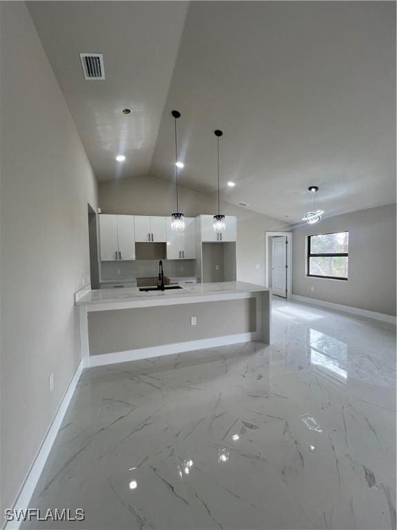 kitchen featuring kitchen peninsula, sink, white cabinets, hanging light fixtures, and lofted ceiling