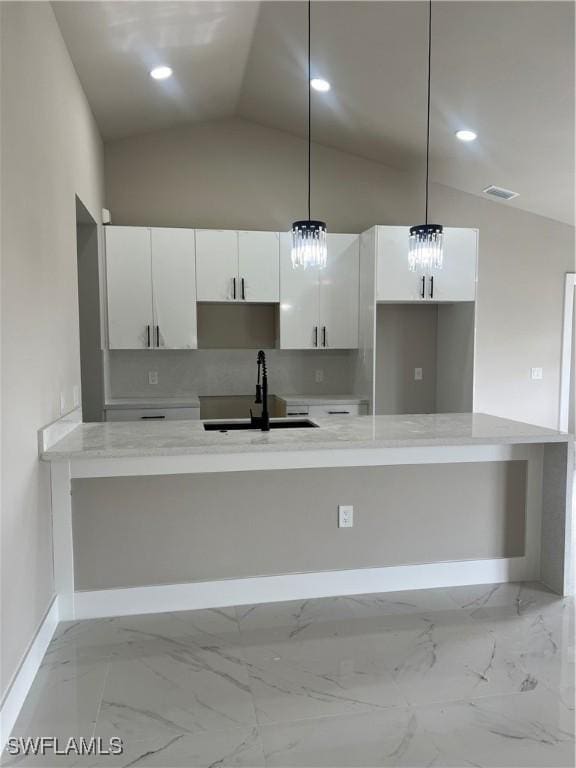 kitchen featuring pendant lighting, white cabinetry, sink, and vaulted ceiling