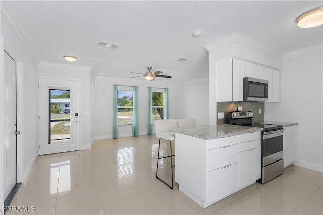 kitchen featuring white cabinets, appliances with stainless steel finishes, a breakfast bar, and light tile patterned floors