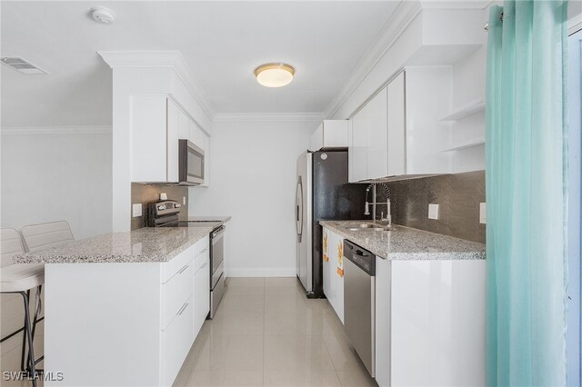 kitchen with a kitchen breakfast bar, backsplash, stainless steel appliances, sink, and white cabinets