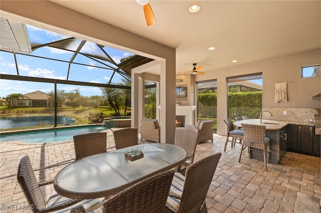 sunroom / solarium featuring exterior fireplace, ceiling fan, and a water view