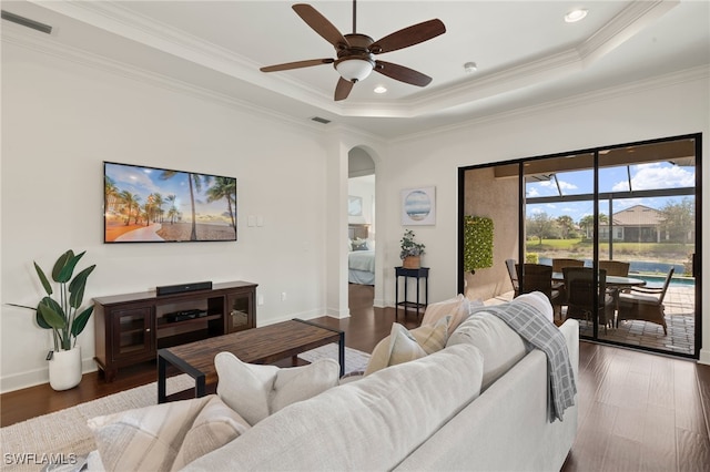 living room featuring a tray ceiling, ornamental molding, and dark hardwood / wood-style floors