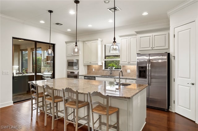 kitchen with sink, light stone counters, a center island, appliances with stainless steel finishes, and pendant lighting