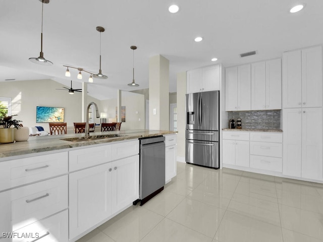 kitchen with sink, hanging light fixtures, light stone countertops, appliances with stainless steel finishes, and white cabinets