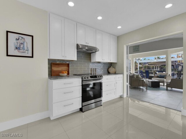 kitchen with tasteful backsplash, light tile patterned flooring, white cabinets, and electric range