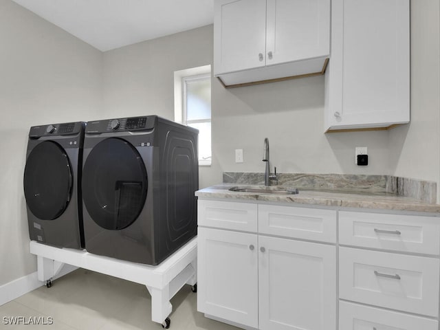 laundry room with cabinets, light tile patterned floors, washing machine and clothes dryer, and sink