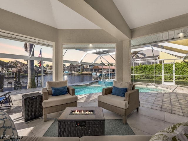 patio terrace at dusk with a water view, an outdoor fire pit, and a lanai