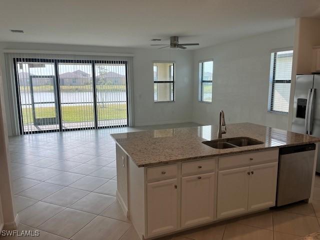 kitchen with sink, stainless steel appliances, a water view, a center island with sink, and white cabinets