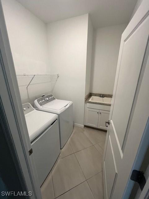 washroom featuring light tile patterned floors, sink, and washing machine and clothes dryer