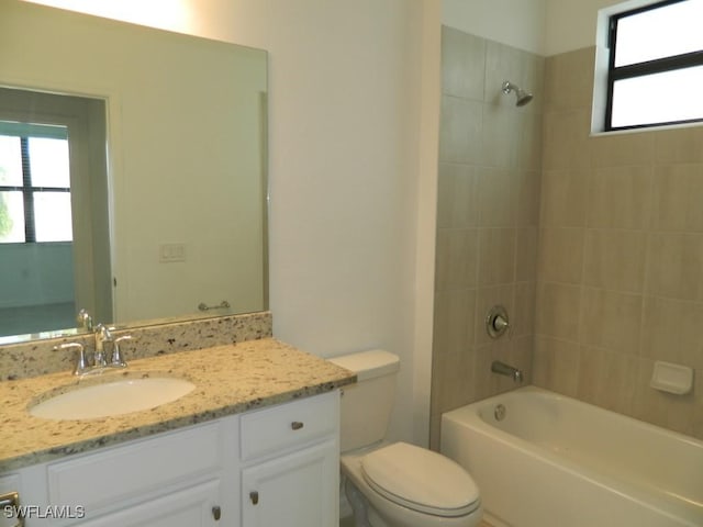 full bathroom featuring vanity, tiled shower / bath combo, and toilet