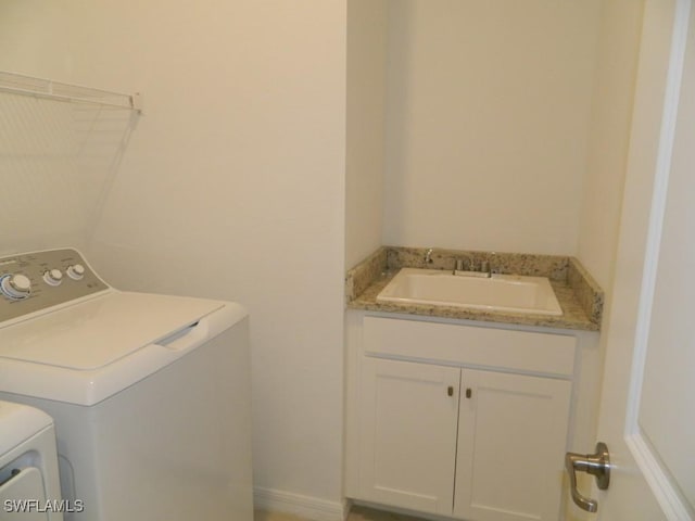 washroom with cabinets, washer and clothes dryer, and sink