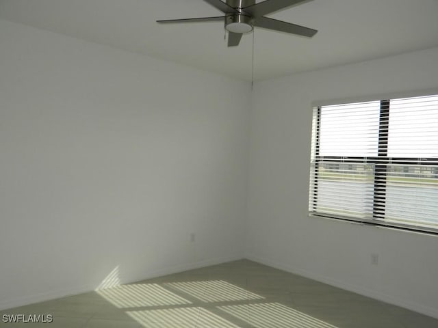 tiled empty room featuring ceiling fan