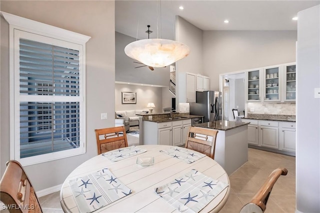 tiled dining area featuring sink and a towering ceiling