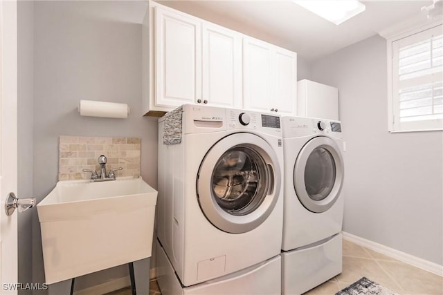 washroom featuring washing machine and clothes dryer, sink, light tile patterned floors, and cabinets