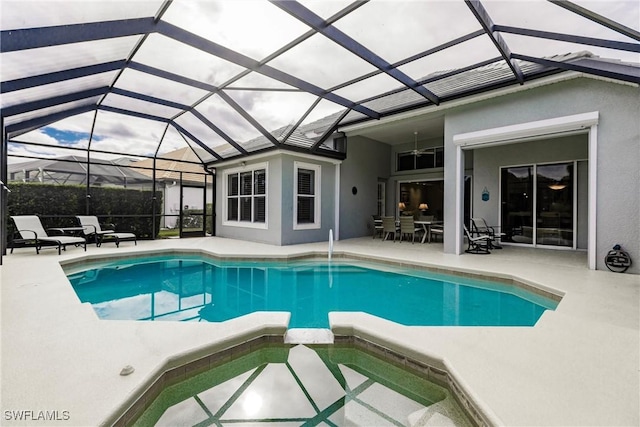 view of pool featuring glass enclosure, a patio area, and an in ground hot tub