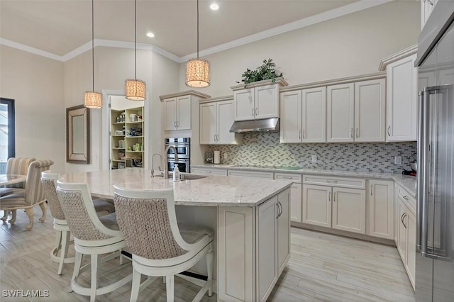 kitchen featuring pendant lighting, backsplash, an island with sink, and appliances with stainless steel finishes