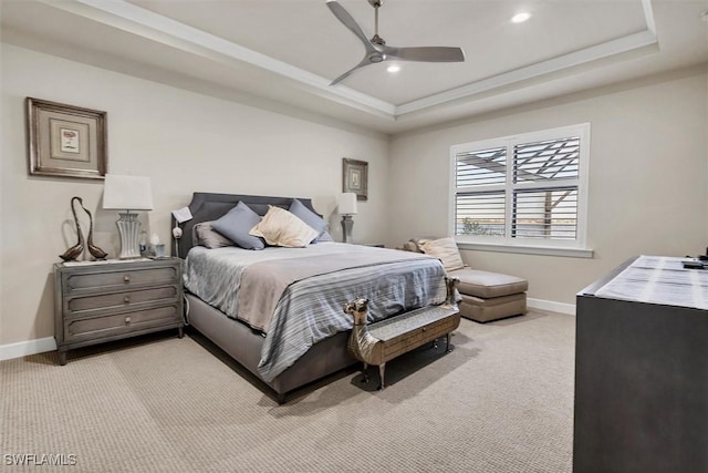 carpeted bedroom with a raised ceiling and ceiling fan