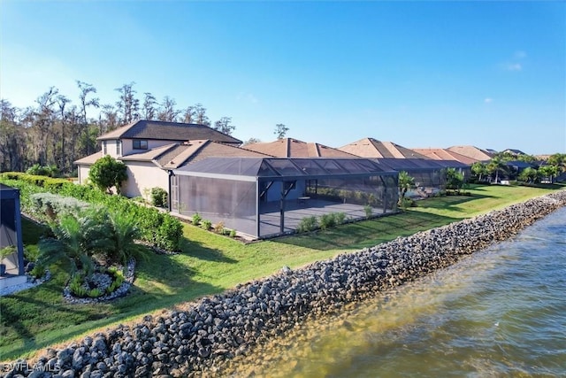 rear view of property with a lanai, a yard, and a water view