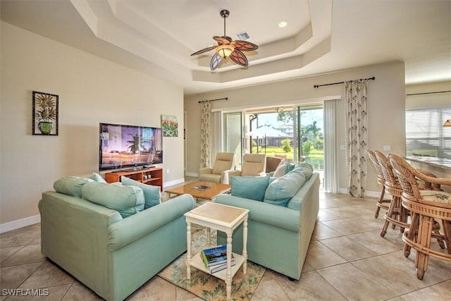 tiled living room featuring a tray ceiling and ceiling fan