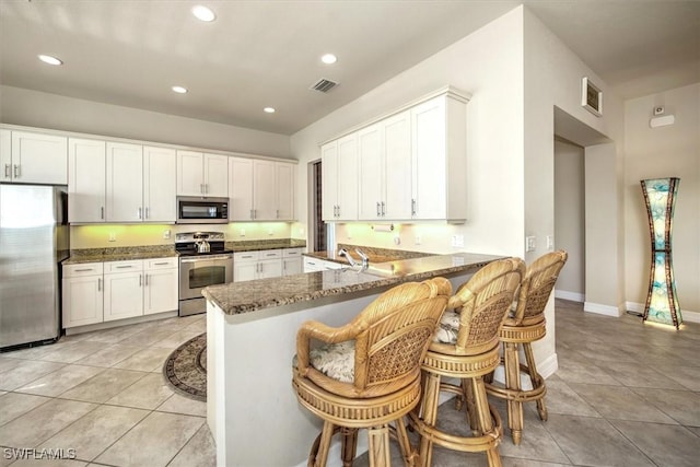 kitchen featuring white cabinets, kitchen peninsula, and stainless steel appliances