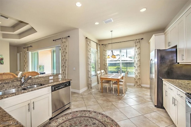 kitchen with white cabinets, sink, appliances with stainless steel finishes, decorative light fixtures, and light stone counters