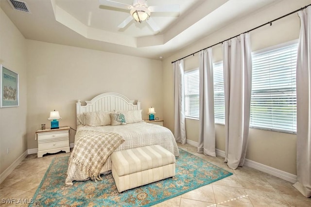 bedroom with a raised ceiling, ceiling fan, and light tile patterned floors