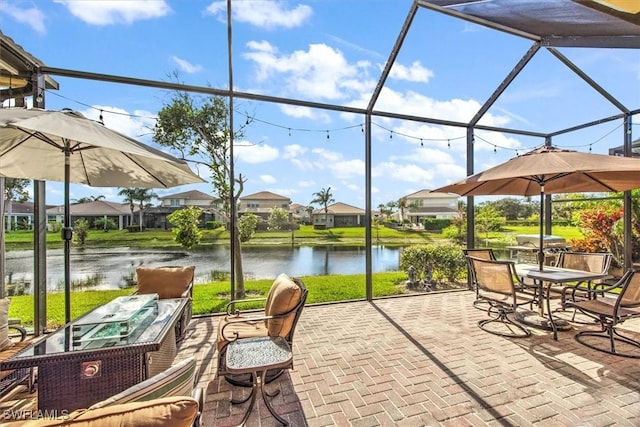 view of patio with glass enclosure and a water view