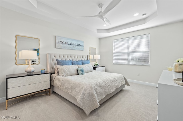 bedroom featuring ceiling fan, recessed lighting, light carpet, baseboards, and a tray ceiling