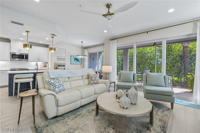 living area with light wood-style flooring, visible vents, a ceiling fan, and recessed lighting