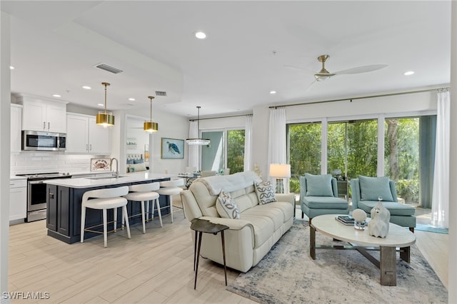 living area with ceiling fan, light wood-type flooring, visible vents, and recessed lighting