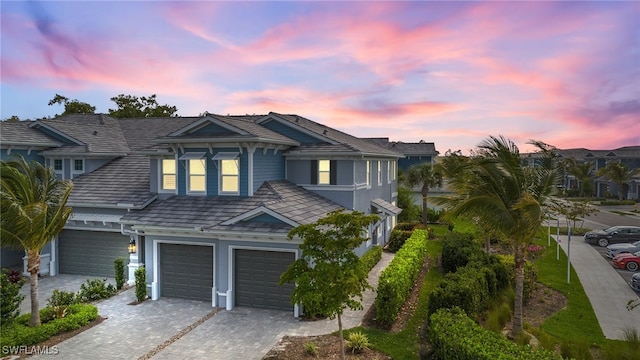 view of front facade featuring decorative driveway, an attached garage, and stucco siding