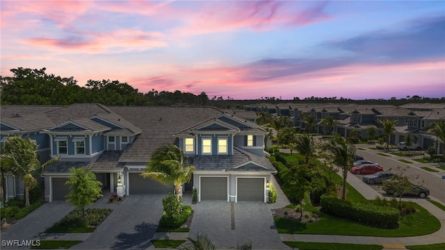 view of front of house featuring a garage, a residential view, decorative driveway, and a tile roof