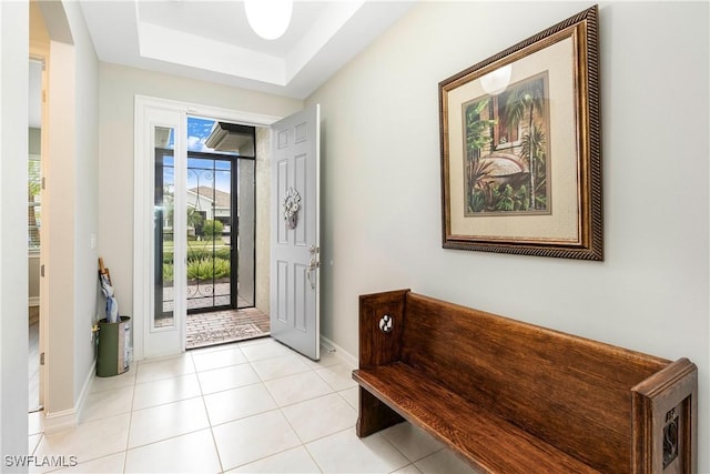 foyer entrance with a raised ceiling, baseboards, and light tile patterned floors